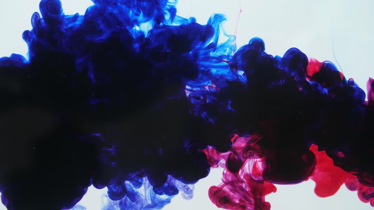 Red And Blue Ink Mixing In Water On A White Background