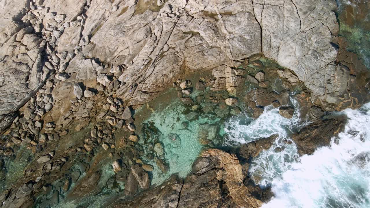 Turista che nuota da solo in una bellissima piscina naturale rocciosa e limpida con onde bianche che si infrangono, vista drone, Greenly Beach, penisola di Eyre, Australia Meridionale
