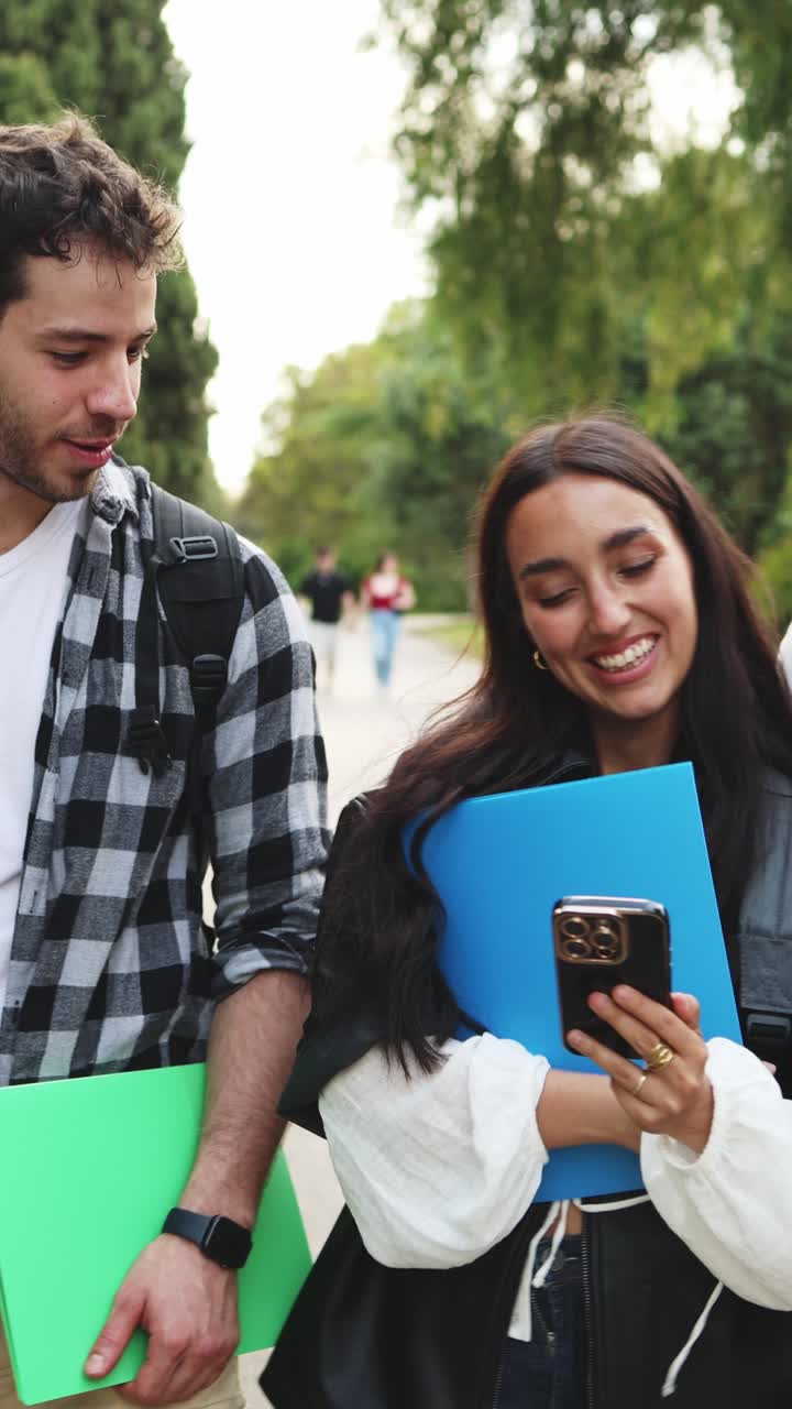 Jóvenes estudiantes felices mirando sus teléfonos inteligentes y riendo al aire libre