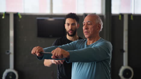 senior man working out with personal trainer at the gym