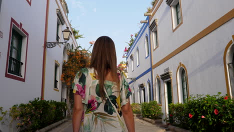 gimbal shot following young woman walking on picturesque white village