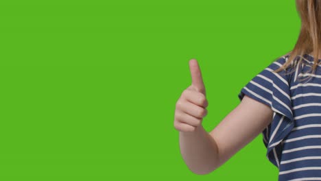 close up of young girl giving thumbs up gesture to camera against green screen 1