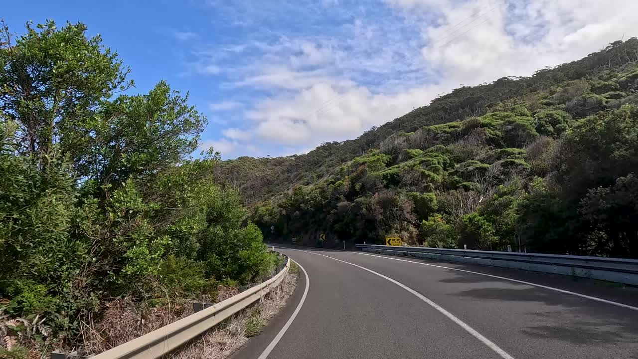 A serene drive through lush landscapes and winding roads under clear skies on the Great Ocean Road