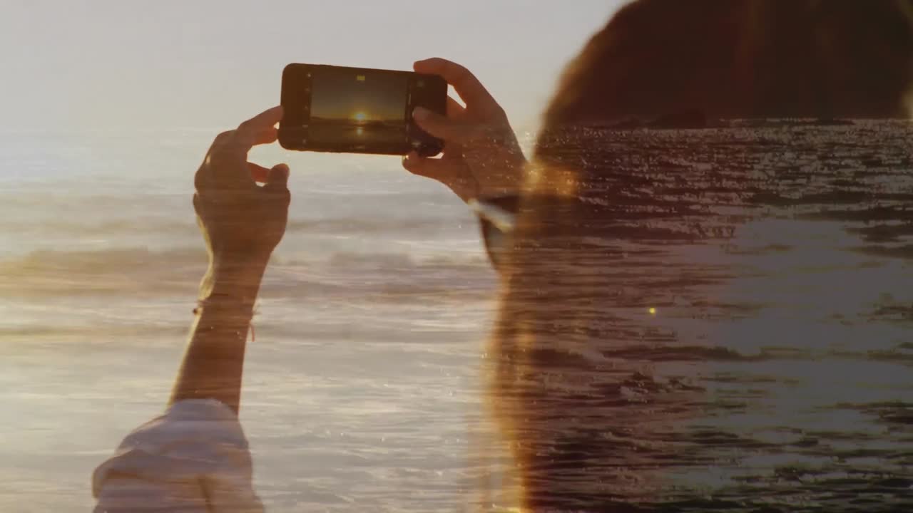 mujer tomando una foto en la playa durante el atardecer