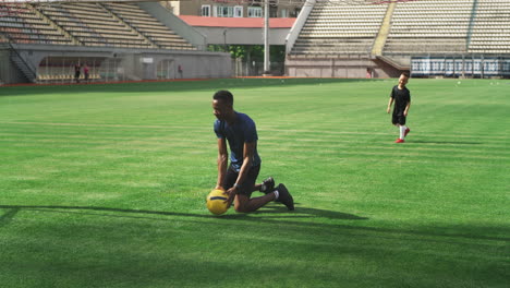 soccer coach and young player practicing on stadium field
