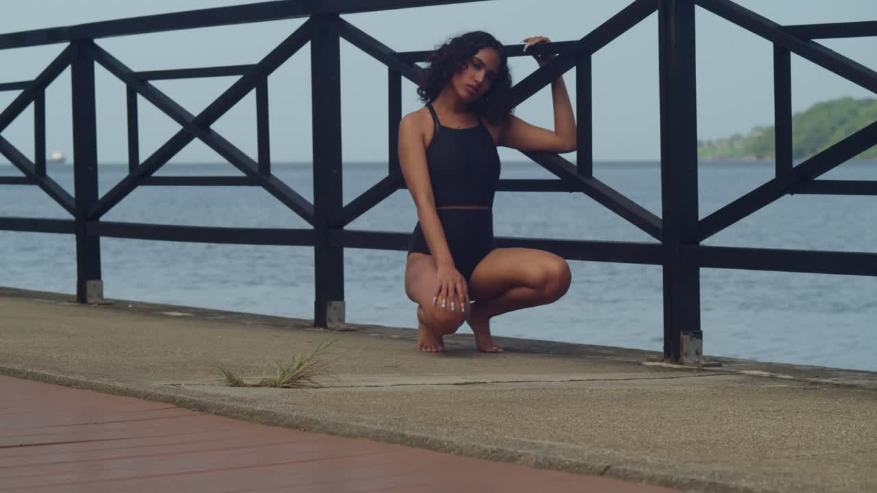 Beautiful Woman in Black Swimsuit Posing on a Tropical Pier
