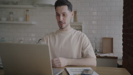 man working from home kitchen on laptop