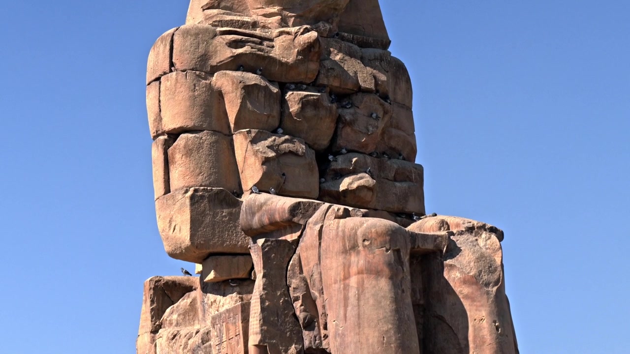 Mısır'ın Luksor Batı Yakası'nda bulunan ikinci Memnon Heykeli'nin üst kısmını gösteren orta, alçak açılı bir çekim.