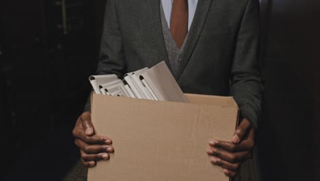 un hombre de negocios afroamericano llevando una caja de carpetas