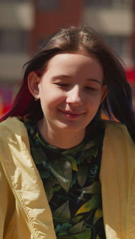 girl with dark straight hair sits on swing in modern city. female teenager smiles cheerfully looking at camera closeup on blurred background