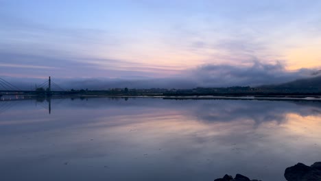 Lapso-De-Tiempo-Del-Lago-Con-Reflejos-De-Nubes-Envueltos-En-Niebla-Al-Amanecer