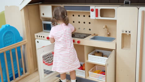 Toddler-Girl-Pretend-Being-Chef-Preparing-Food-on-Gas-Range-in-Toy-Kitchen