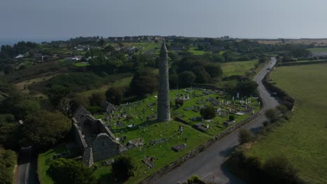 st. declan's monastery, ardmore, county waterford, ireland, september 2024. drone orbits counter clockwise around the historic round tower and graveyard with the north atlantic ocean in the distance.