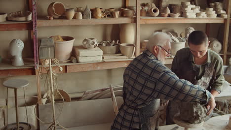 senior man and young woman making sculpture in workshop