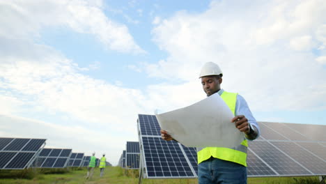 bottom view of young african american engineer holding and looking at solar plan on solar plantation