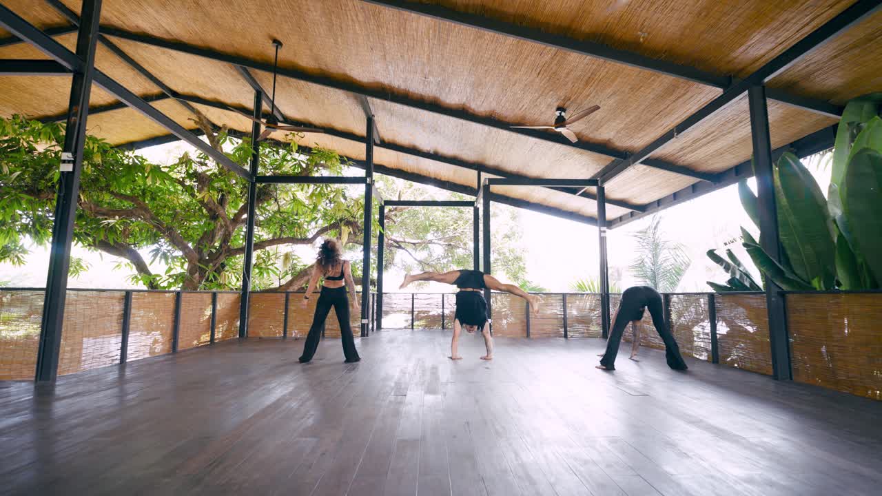 Gruppo di ballerini che eseguono movimenti di danza contemporanea in uno studio all'aperto.