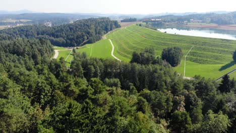 trash landfill terraces with grass on top on chemical disposal lakeshore, aerial approach view