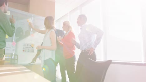 Team-of-business-executives-discussing-over-glass-board