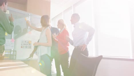 equipo de ejecutivos de negocios discutiendo sobre un tablero de vidrio