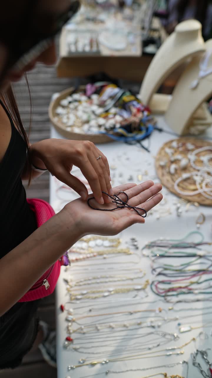 mujer mirando una pulsera de cuentas en un mercado al aire libre