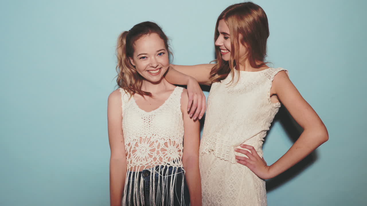 두 명의 젊은 여성, 친구들이 스튜디오에서 포즈를 취하고 있습니다.