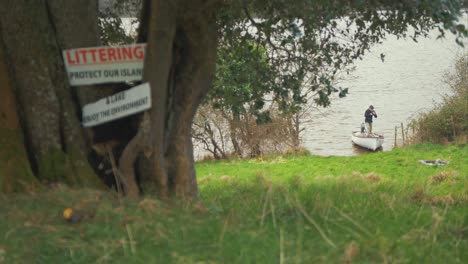 Young-man-beaching-boat-on-island-shoreline-Protect-Island-Sign