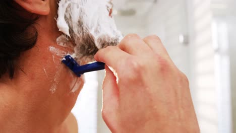 man using a razor to shave his beard off