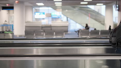 woman rides moving walkway from left to right while wearing a mask