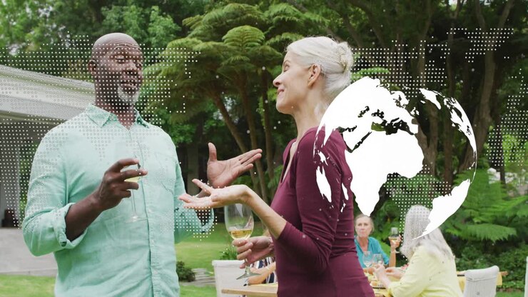 Man starting talk while woman responding holding wine during yard meal, tech globe overlaying right