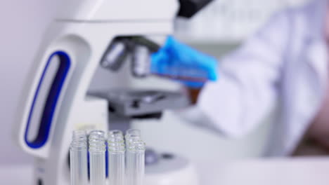 microscopio, muestra y manos de científico