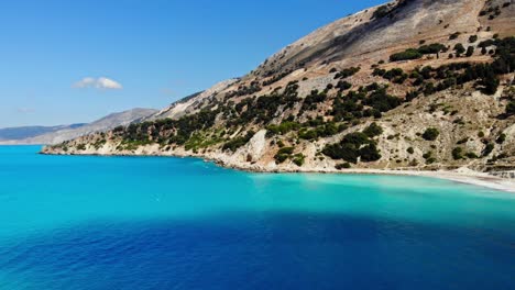 calm blue ocean and lush cliffs at agia kiriaki beach in greece - aerial drone shot