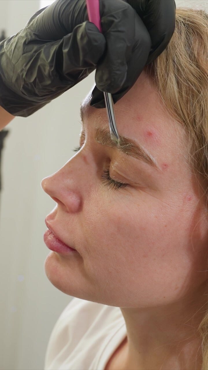Close up view of woman face as eyebrow specialist shapes her eyebrows using tweezers. scene shows detailed interaction between professional and client in calm indoor environment focusing