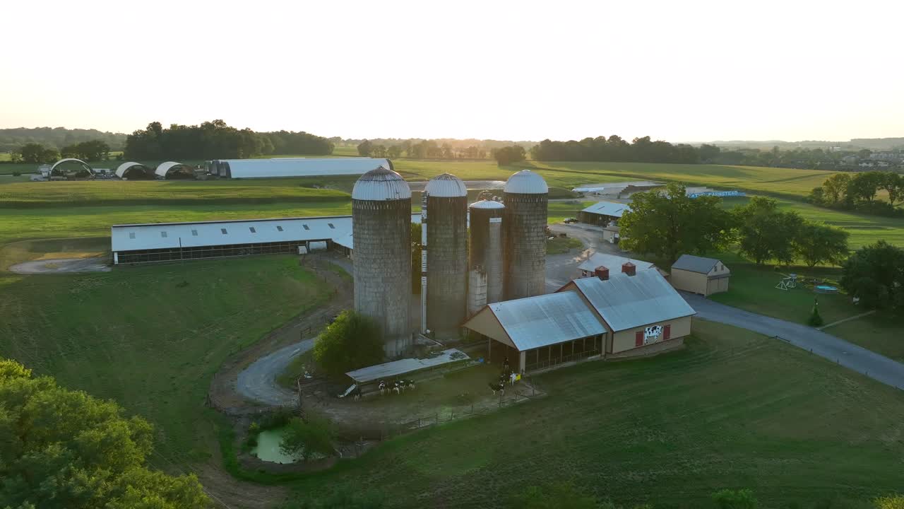 puesta de sol sobre una granja con silos y graneros largos en un paisaje rural