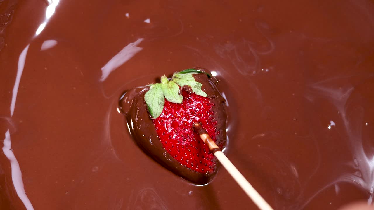 녹은 초콜릿 에 딸기 를 담그고 있는 것
