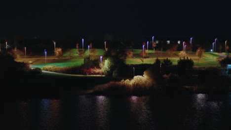 beautiful landscape of pae park alongside pond illuminated with night light, tallinn, estonia