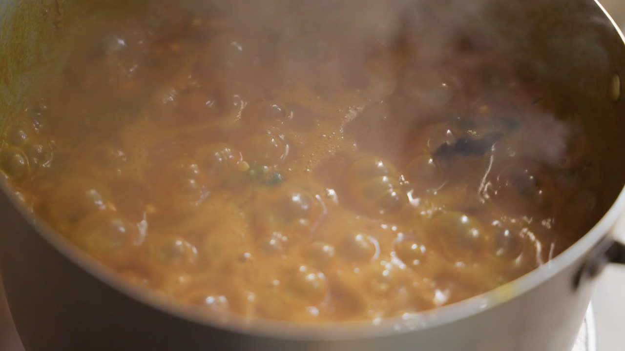 Ampio stufato che sobbolle in pentola, cucchiaio che mescola salsa densa, utensile scuro che raschia i bordi, densa nuvola di vapore, casseruola di metallo sul fornello, tecnica da chef, preparazione attiva della ricetta, energia rustica della cucina