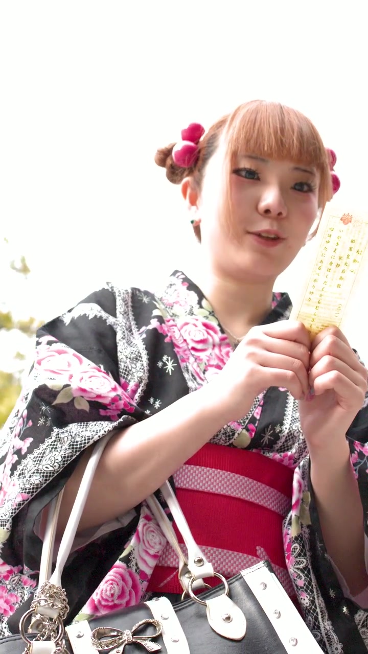 Una giovane donna in kimono tradizionale legge un biglietto della fortuna all'aperto in un santuario giapponese.