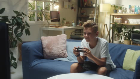 young boy playing video games on the couch