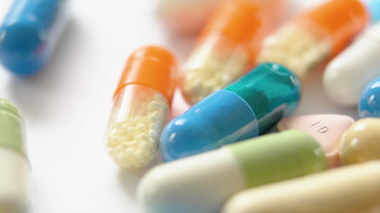 very bright moving close-up of several cellulose capsules containing powder or granules, on a white surface