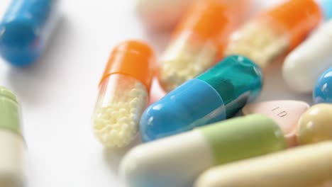 very bright moving close-up of several cellulose capsules containing powder or granules, on a white surface