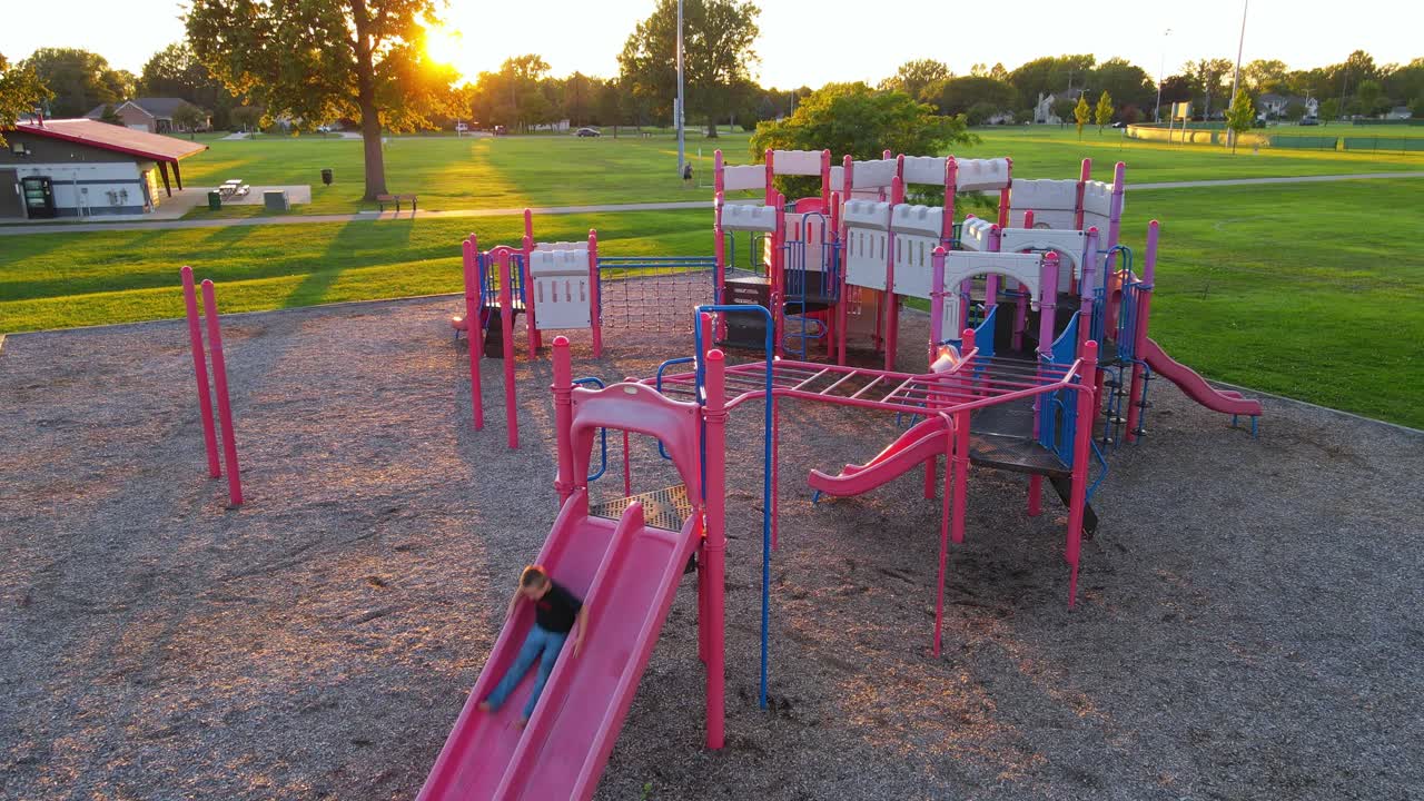 Happy child on slide in playground, aerial drone view on sunny evening