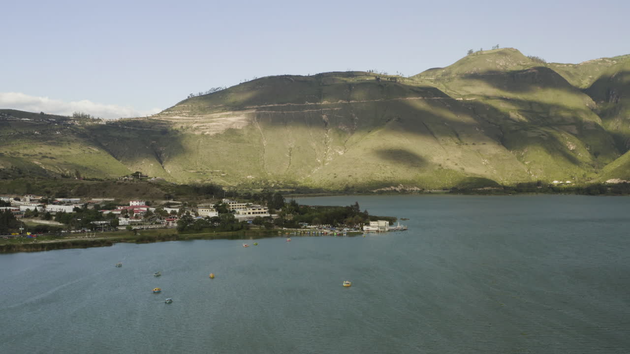 Scenic Landscape of a Lakeside Village with Mountains and Boats
