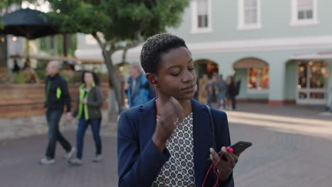 Retrato-De-Una-Mujer-De-Negocios-Afroamericana-Segura-De-Sí-Misma-Usando-Auriculares-Escuchando-Música-Esperando-En-La-Ciudad