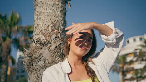 carefree woman enjoying summer at palm tree place portrait. girl covering face