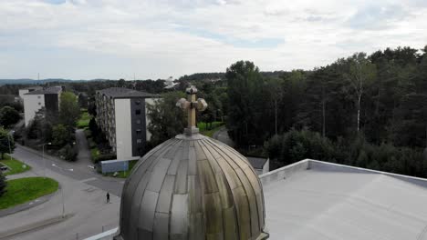 Vogel,-Der-Von-Einem-Kirchenkreuz-Wegfliegt,-Luftaufnahme,-Umlaufbahn,-Drohnenaufnahme