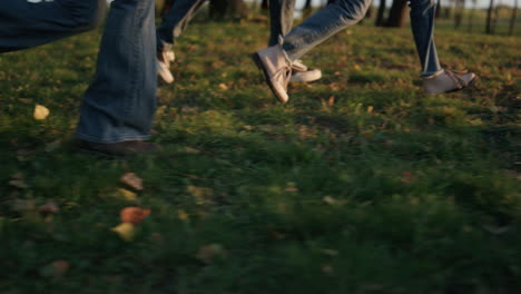 Piernas-Familiares-Corriendo-Parque-Campo-Luz-Dorada-Del-Sol-Primer-Plano.-Ocio-Al-Aire-Libre-De-Otoño.