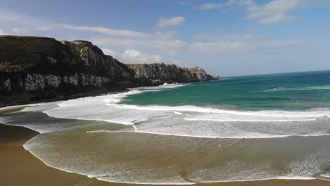 Puranakanui-bay-cliffs-aerial-fly-forward-to-the-cliffs-in-sunny-day,-beautiful-surfing-spot-in-The-Catlins,-New-Zealand