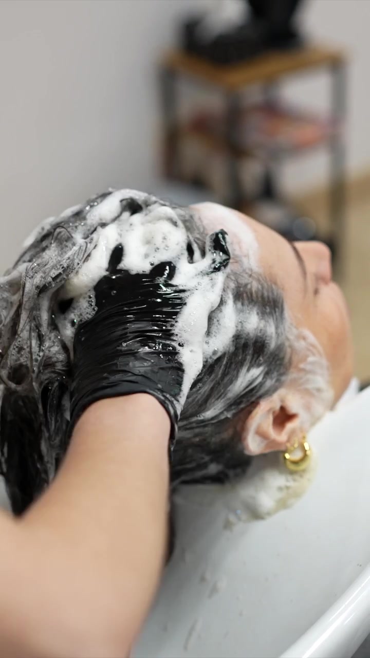 Parrucchiera che lava i capelli della cliente in salone