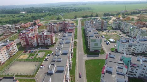 cars are passing along the road of the new district of the city on the background of high-rise buildings near the construction of modern buildings. aerial view