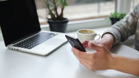 mujer usando la aplicación en el teléfono inteligente en una cafetería bebiendo café sonriendo y enviando mensajes de texto en el teléfono móvil. hermosa joven profesional femenina